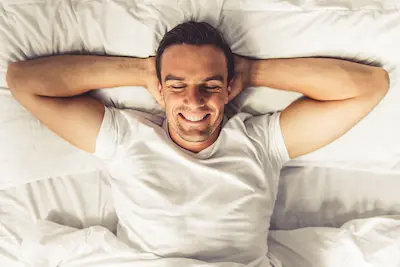 Mladý smějící se muž v posteli