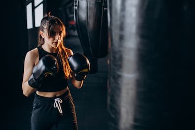Mladá žena boxuje s boxovacím pytlem