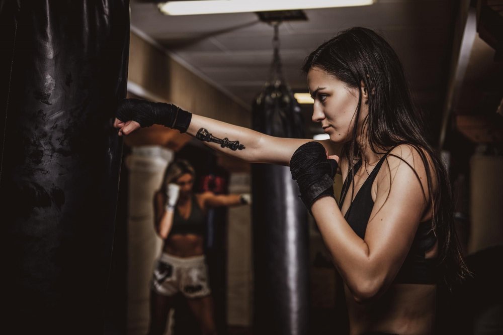 Mladá žena boxuje do boxovacího pytle 