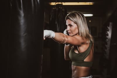 Mladá blond žena boxuje do boxovacího pytle