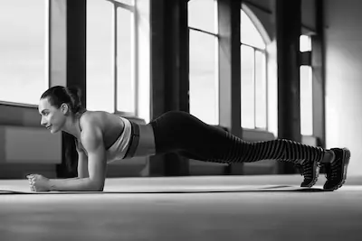 mladá žena cvičí plank v tělocvičně