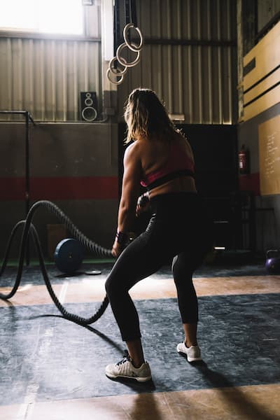 silná mladá žena cvičí v posilovně s lany